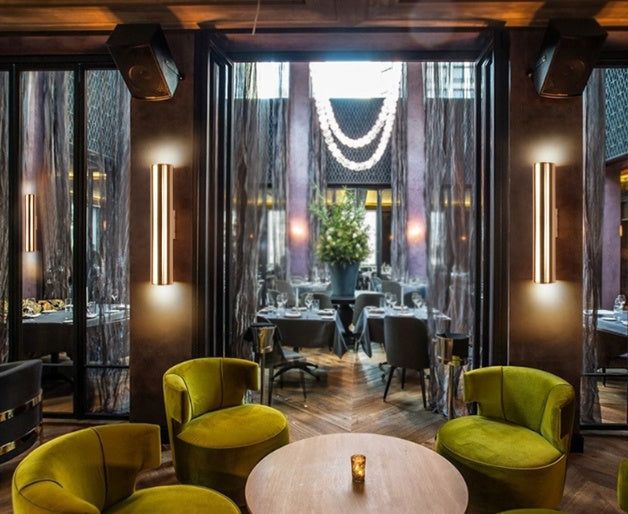 Vintage iron wall lamp by WinniHouse mounted on a wall, showcasing its rustic, industrial design with exposed hardware and warm lighting.