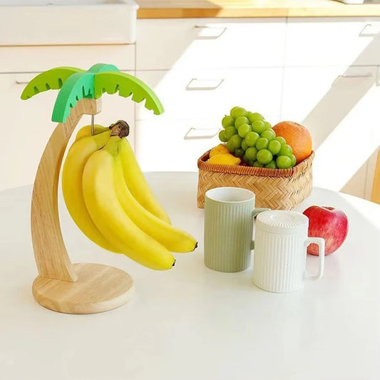 Wooden hanging kitchen shelf in banana shape by WinniHouse, mounted on a wall with visible kitchen items and hooks for storage.